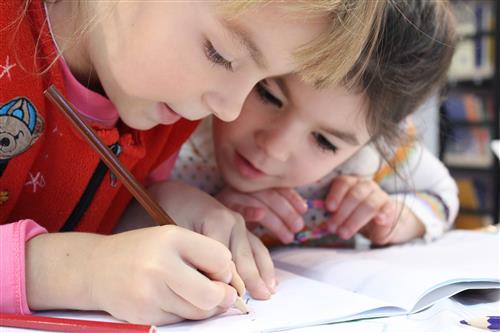 two young school children working together 